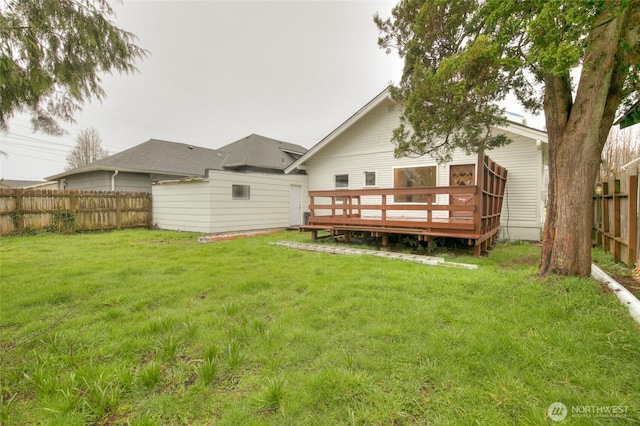 rear view of house with a fenced backyard, a wooden deck, and a yard