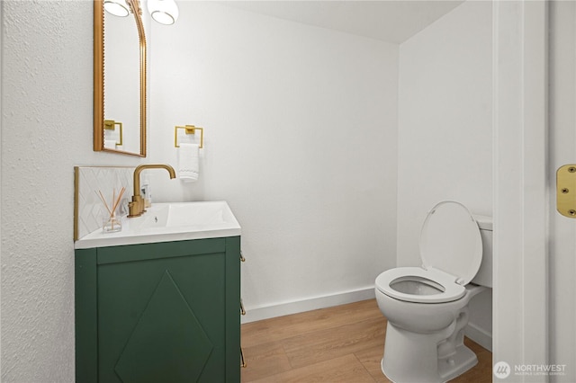 bathroom featuring toilet, vanity, baseboards, and wood finished floors