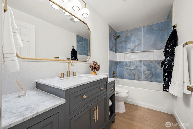 full bathroom with vanity, wood finished floors, washtub / shower combination, decorative backsplash, and toilet