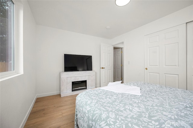 bedroom with a premium fireplace, baseboards, and wood finished floors