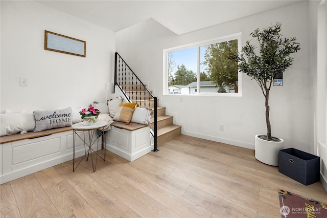 living area with stairway, baseboards, and light wood-style flooring