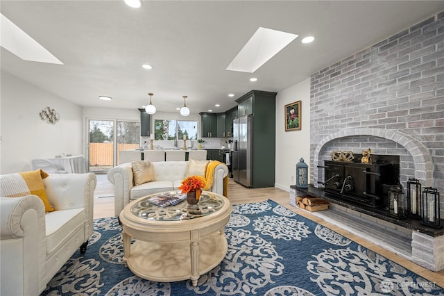 living area featuring a fireplace, a skylight, recessed lighting, and light wood-type flooring