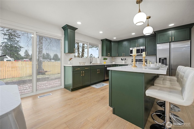 kitchen featuring green cabinets, light countertops, light wood-type flooring, and stainless steel appliances