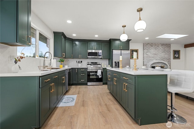 kitchen featuring a breakfast bar, light countertops, appliances with stainless steel finishes, and green cabinetry