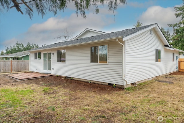 back of property with a patio area, a yard, fence, and roof with shingles