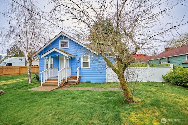 bungalow-style house with a front lawn and fence