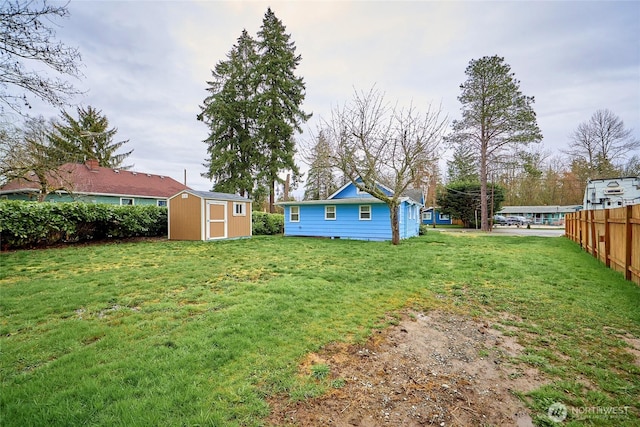 view of yard featuring an outbuilding, fence, and a shed