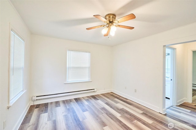 unfurnished room with a baseboard heating unit, baseboards, and wood finished floors