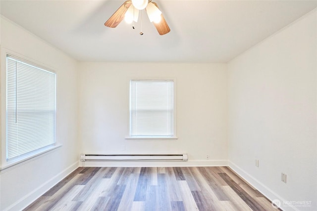 spare room featuring a wealth of natural light, wood finished floors, baseboards, and baseboard heating