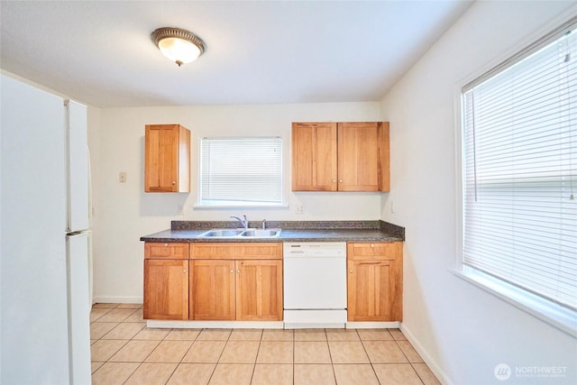 kitchen with dark countertops, dishwasher, a wealth of natural light, and a sink