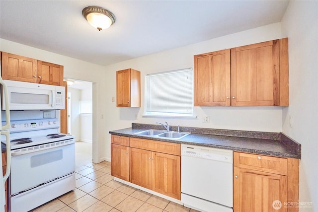 kitchen featuring dark countertops, a healthy amount of sunlight, light tile patterned floors, white appliances, and a sink