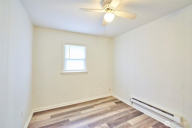 spare room with baseboards, baseboard heating, wood finished floors, and a ceiling fan