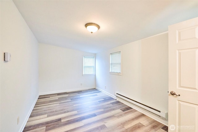 empty room with light wood finished floors, baseboards, and baseboard heating