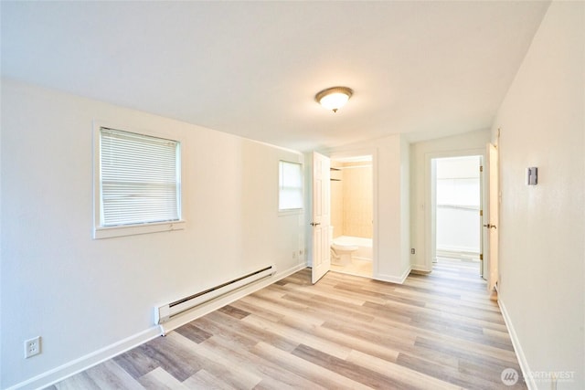 empty room with a baseboard heating unit, light wood-style floors, and baseboards