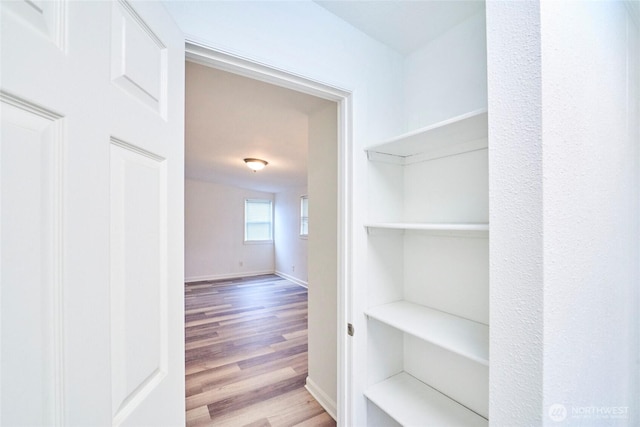 corridor with baseboards and wood finished floors