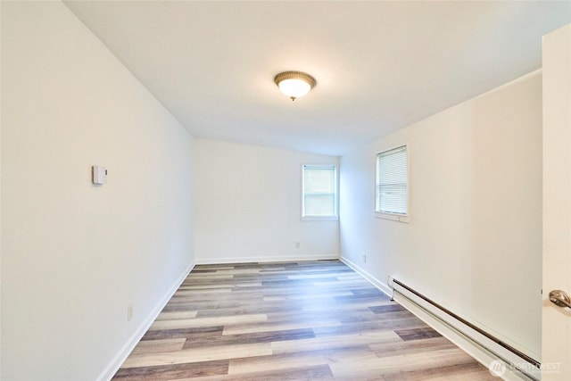 unfurnished room with wood finished floors, baseboards, and a baseboard radiator