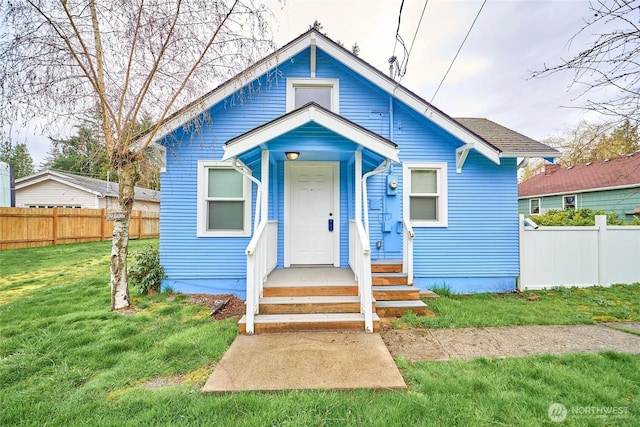 bungalow with a front yard and fence