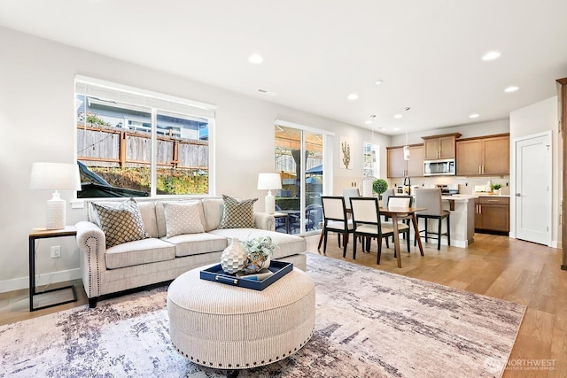 living room featuring light wood finished floors, recessed lighting, and baseboards