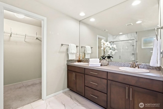 bathroom with a sink, marble finish floor, a stall shower, and a spacious closet