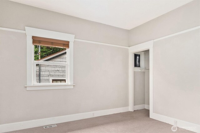 empty room featuring visible vents, carpet floors, and baseboards