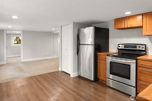 kitchen with brown cabinets, wood finished floors, recessed lighting, appliances with stainless steel finishes, and baseboards