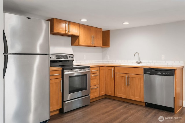 kitchen featuring dark wood-type flooring, a sink, recessed lighting, stainless steel appliances, and brown cabinetry