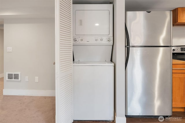 laundry area with visible vents, baseboards, carpet floors, laundry area, and stacked washing maching and dryer