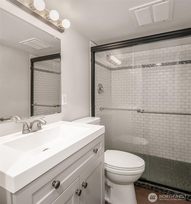 full bathroom featuring vanity, toilet, visible vents, and a stall shower