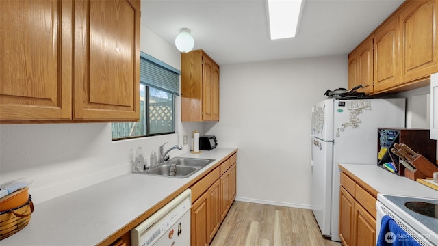 kitchen with white appliances, baseboards, light wood-style flooring, a sink, and light countertops