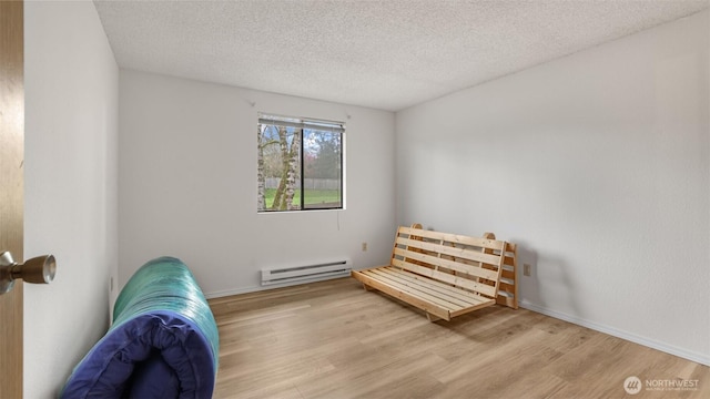 sitting room featuring baseboard heating, a textured ceiling, baseboards, and wood finished floors