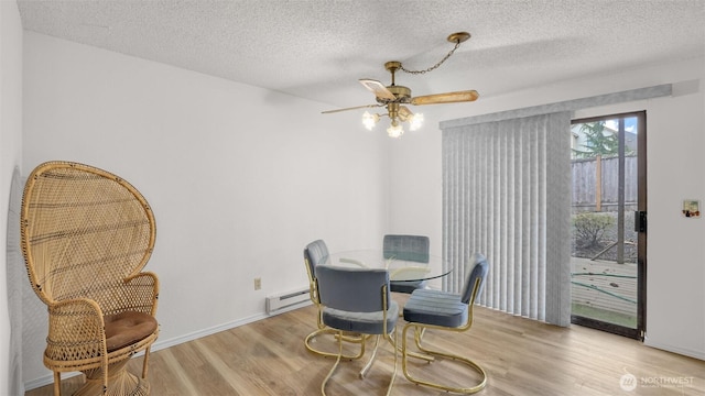 dining area featuring a baseboard heating unit, ceiling fan, wood finished floors, and a textured ceiling