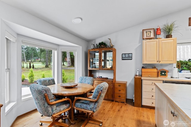 dining space with a wealth of natural light, lofted ceiling, and light wood-style floors