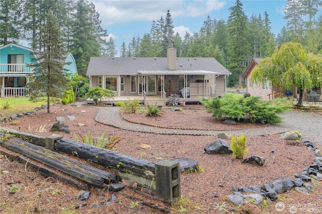 rear view of property featuring a chimney and a deck