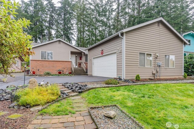 ranch-style house with brick siding, driveway, an attached garage, and a front lawn