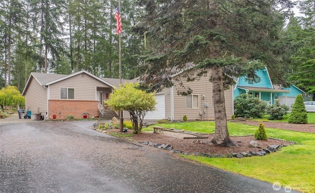 ranch-style home with a garage, a front yard, brick siding, and driveway