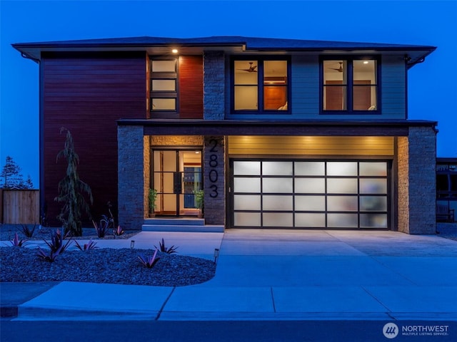 view of front of house with stone siding, driveway, and fence