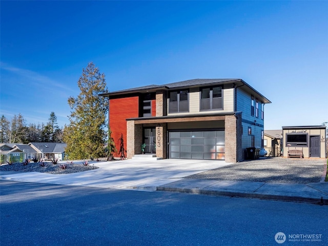 contemporary home with a garage, brick siding, and driveway