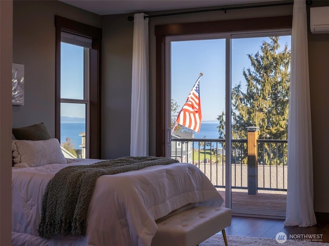 bedroom featuring access to outside, wood finished floors, a water view, and a wall mounted air conditioner