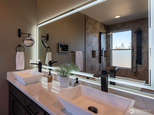 bathroom with double vanity, recessed lighting, a tile shower, and a sink