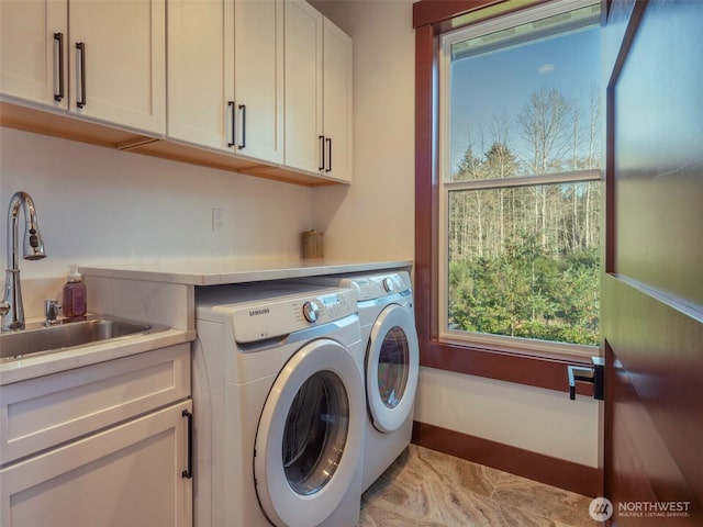 laundry area with a sink, baseboards, cabinet space, and independent washer and dryer