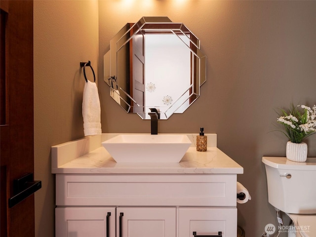 half bathroom featuring vanity and toilet