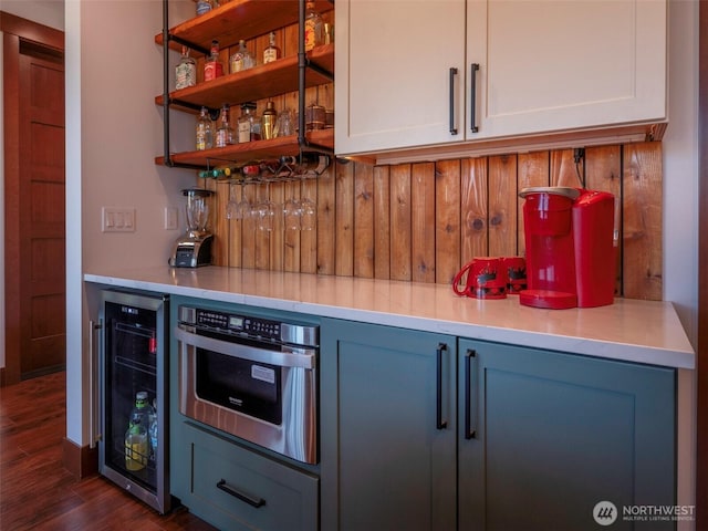 bar with a bar, wine cooler, dark wood-style floors, and oven