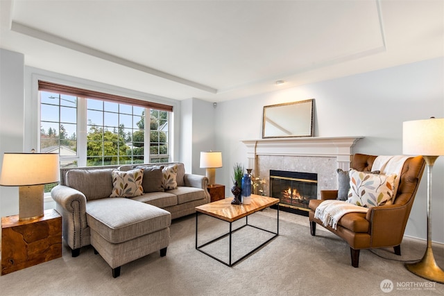 living room with a raised ceiling, light colored carpet, and a high end fireplace