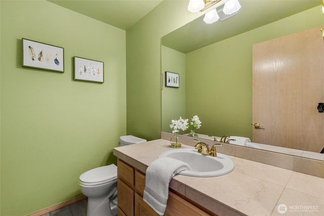 bathroom featuring toilet, vanity, and baseboards