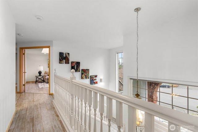 hall with an upstairs landing, baseboards, and wood finished floors