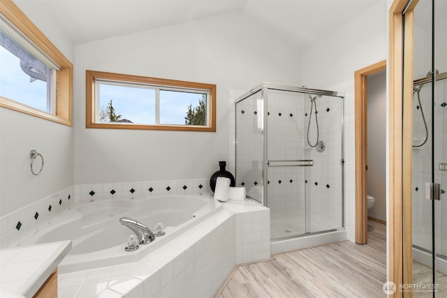 bathroom with a bath, a shower stall, and lofted ceiling