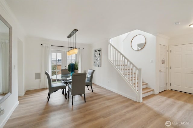 dining space with stairs, light wood-style floors, and baseboards