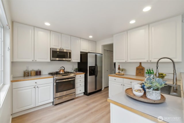 kitchen featuring stainless steel appliances, light wood-style flooring, and white cabinetry