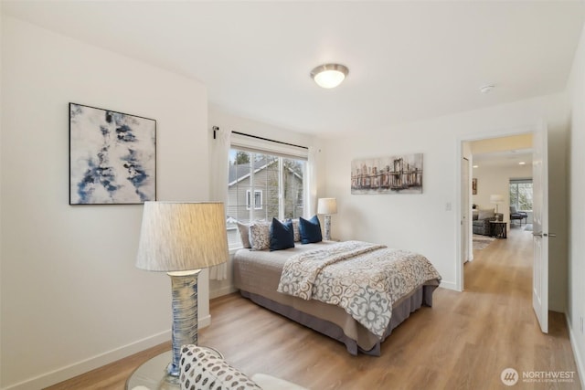 bedroom featuring multiple windows, baseboards, and light wood-type flooring