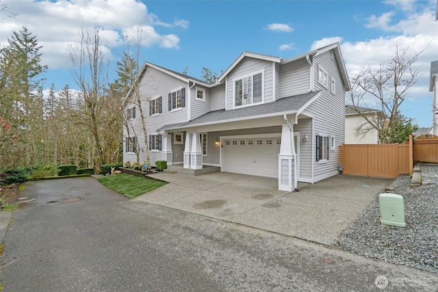 traditional home featuring a shingled roof, concrete driveway, a garage, and fence